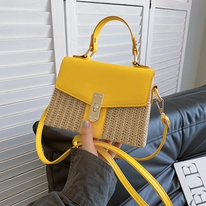 Schultertasche aus Stroh und gelbem Leder mit Metalldrehverschluss auf Ledersofa