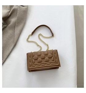 Detail view of brown quilted leather bag with geometric stitching and gold chain strap