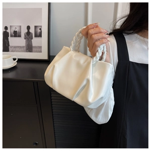 Detail of white pleated cloud bag featuring a unique braided rope handle and soft texture