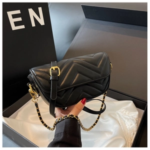 Close-up of black chevron quilted leather shoulder bag with gold chain in a gift box
