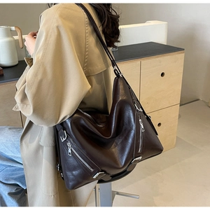 Detail of dark brown tote bag with silver zipper accents and glossy leather texture