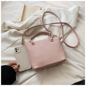Vertical pleated pink mini bucket bag shown next to a smartphone for size reference