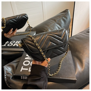 Detail of black quilted leather shoulder bag with chevron stitching and gold chain strap