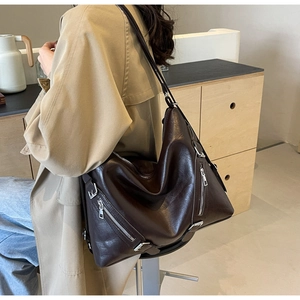 Detail of dark brown leather tote bag with silver zippers and adjustable straps