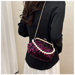 Detail of rose red sequin evening bag with gold clasp and pearl handle on a model