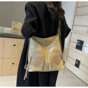 Detail of beige corduroy tote showing heart-shaped pockets and stylish silver tassel zippers