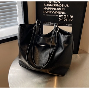 Close-up of black textured leather tote bag with silver hardware and long shoulder straps