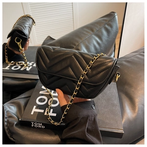 Close-up of black quilted crossbody bag with gold chain strap and elegant chevron stitching