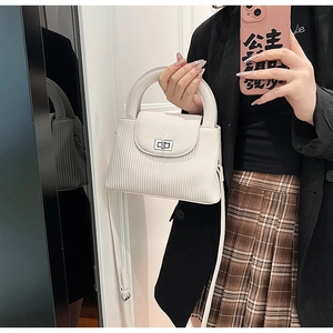 Detail view of white ribbed texture crossbody bag with silver clasp and top handle