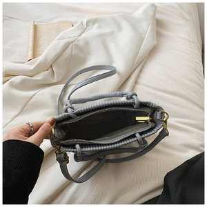 Detailed interior of pleated bucket bag with grey lining and golden metal zipper hardware