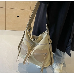 Detail of khaki canvas hobo bag featuring decorative heart shaped zipper pockets