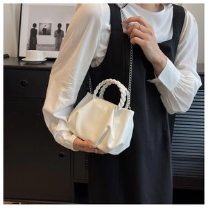 Detailed view of white pleated cloud bag with woven handles and silver chain strap