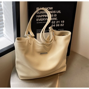 Close-up of cream white tote bag with lychee texture leather and silver metal buckle
