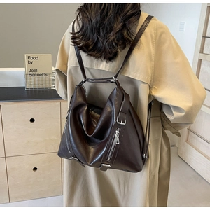 Detail of dark brown leather tote bag with functional zippers and adjustable straps