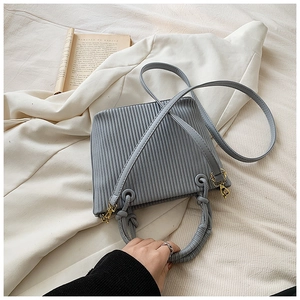 Detail of grey pleated bucket bag featuring elegant gold hardware and top handle design