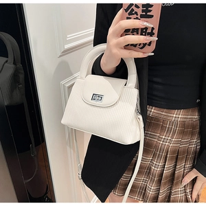 Detail of cream white quilted crossbody bag with silver turn-lock and leather strap