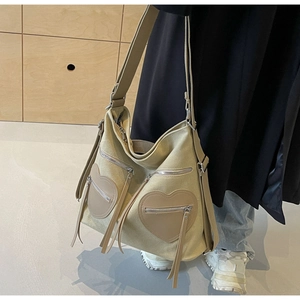 Detail of beige corduroy tote with heart-shaped pockets and long fringe zippers