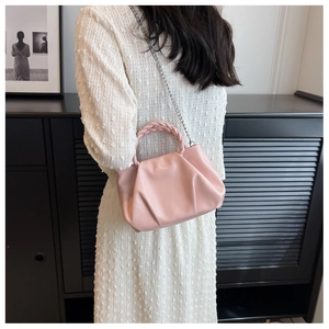 Detail of light pink pleated cloud bag with braided handle and silver chain strap
