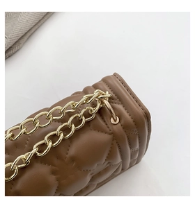 Close-up of brown quilted leather texture and light gold chain strap on the handbag