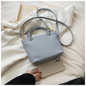 Detailed top view of the light blue pleated bucket bag with phone and book for size scale