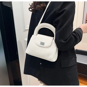 Detail view of white quilted crossbody bag with silver rotating lock on black blazer