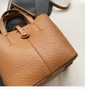 Detail view of brown lychee-patterned leather bucket bag with top handle and strap
