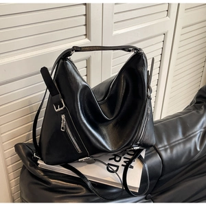 Detail view of black tote bag showing smooth leather texture and silver zipper accents