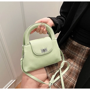 Detail of light green textured handbag with silver twist lock and vertical stripe pattern