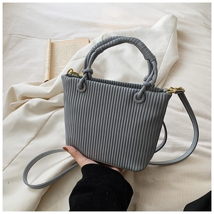 Detailed view of grey pleated bucket bag texture with gold hardware on white fabric