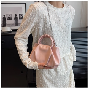 Close-up of pink pleated cloud bag with woven handle and thin metal chain strap