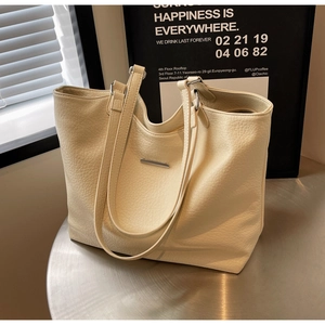Detailed macro view of beige lychee grain leather tote bag with elegant metal accent