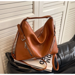 Close-up of brown faux leather tote bag showing smooth texture and silver zippers