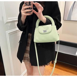 Detail of mint green crossbody bag with vertical stripe texture and silver metal clasp