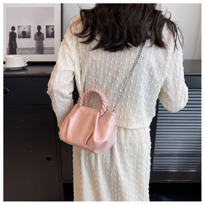 Detail of light pink cloud bag featuring pleated leather texture and a braided handle