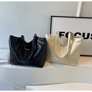 Detailed comparison of black and cream large tote bags in pebbled leather with metal trim