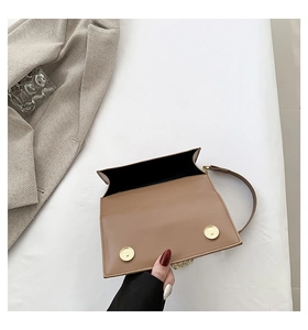 Detail view of the brown leather handbag showing double magnetic clasps and gold chain strap