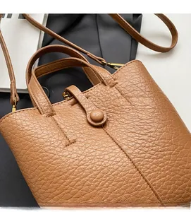 Detailed close-up of dark brown lychee texture leather bucket bag with bronze hardware