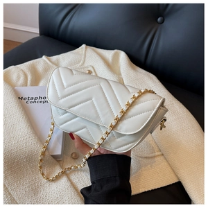 Close-up of V-quilted texture and gold-tone chain strap on white shoulder bag