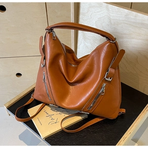 Brown leather tote bag featuring a decorative silver zipper and side buckle detail