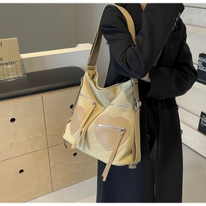 Detailed view of beige corduroy tote with heart leather patches and long fringe tassels