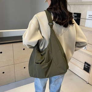 Army green large nylon tote bag with adjustable strap worn by model in a casual setting
