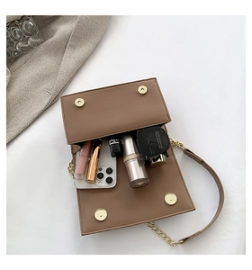 Internal capacity of brown leather square bag showing smartphone and daily essentials