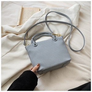 Detail of greyish blue bucket bag with vertical pleated texture and gold hardware