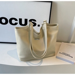 Detailed macro view of the cream lychee grain leather and silver metal bar on a tote bag
