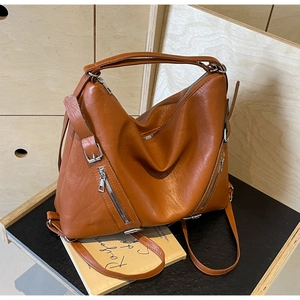 Detail of brown leather tote bag with decorative silver zippers and pebble texture