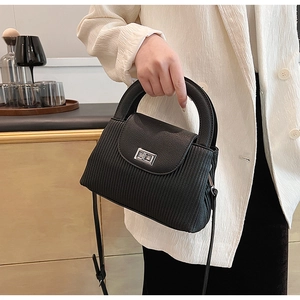 Detail shot of the black pleated handbag with silver twist lock and round handle