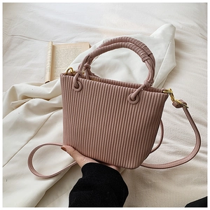 Detail of pink pleated bucket bag showing vertical textures and golden metal hooks