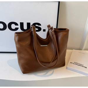 Detailed view of brown tote bag showing lychee grain leather texture and metal buckle