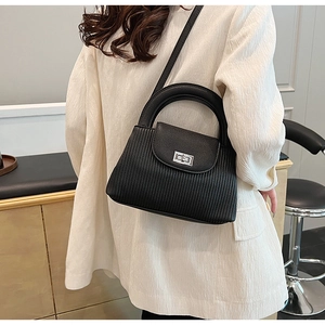 Detail of black pleated faux leather bag with silver metal lock and round handle