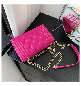 Detailed macro view of quilted diamond pattern and gold chain strap on rose red bag